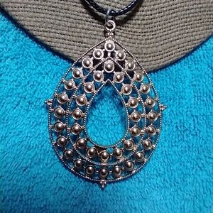 Goldtone intricate design teardrop necklace with black cord